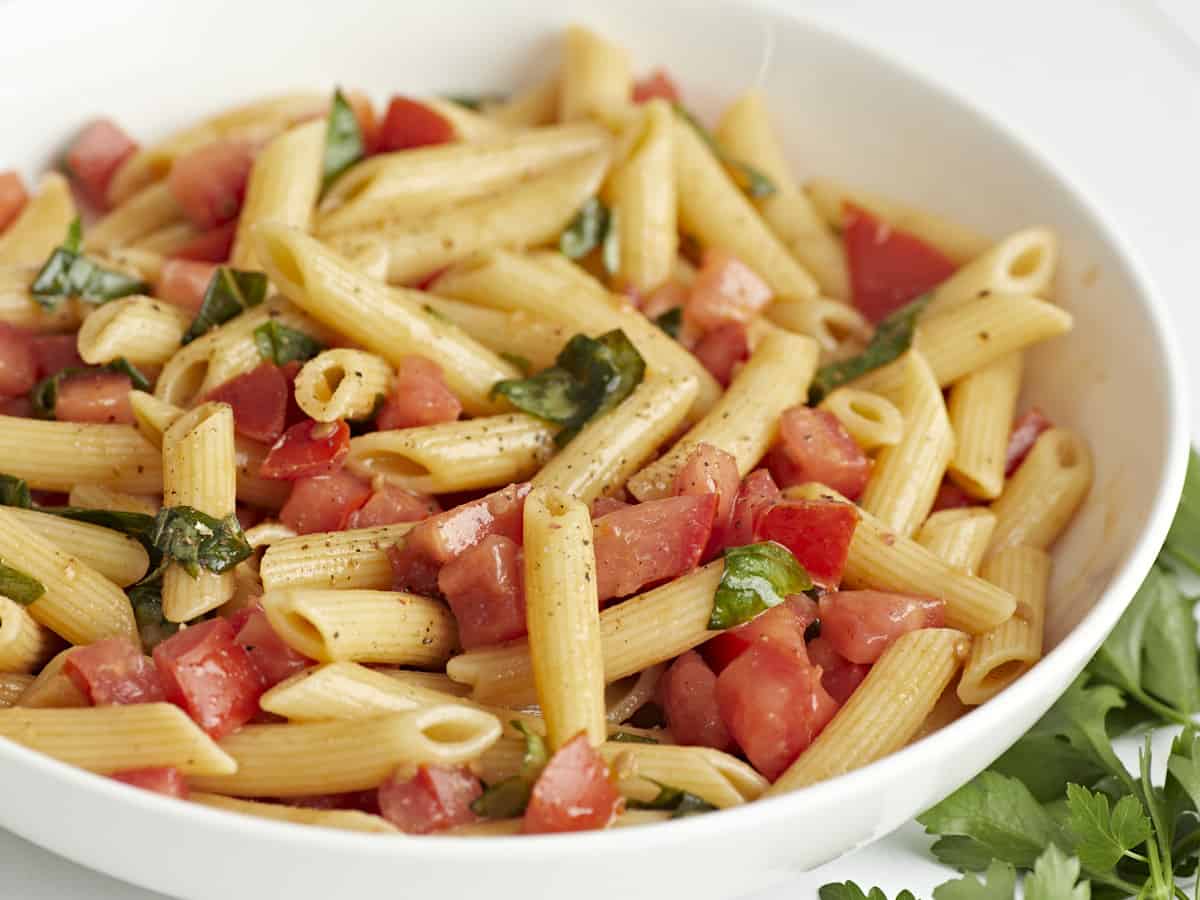 Close up side view of a bowl full of bruschetta pasta.