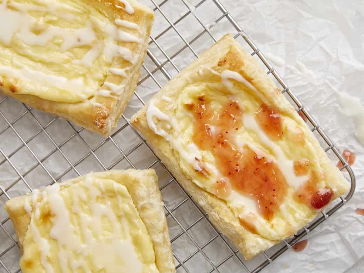 Overhead shot of three cheese danish on a cooling rack.