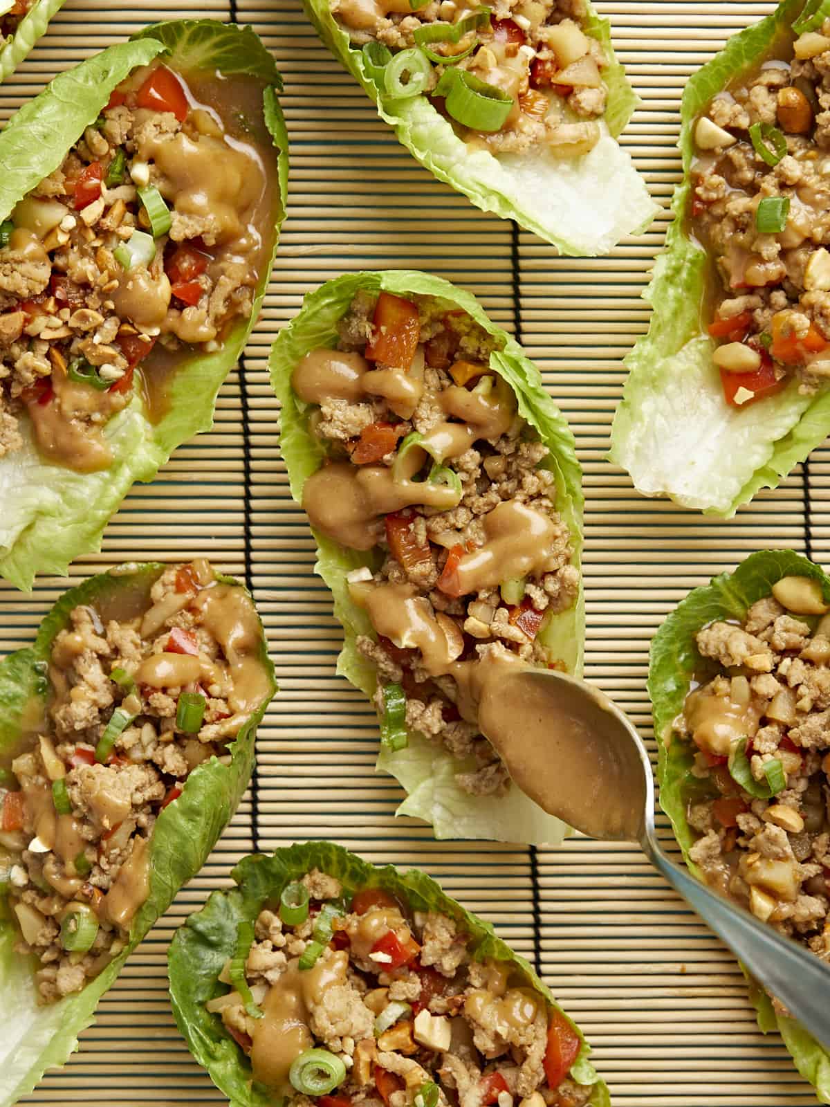 close up shot of chicken lettuce wraps with peanut lime dressing being drizzled on top.