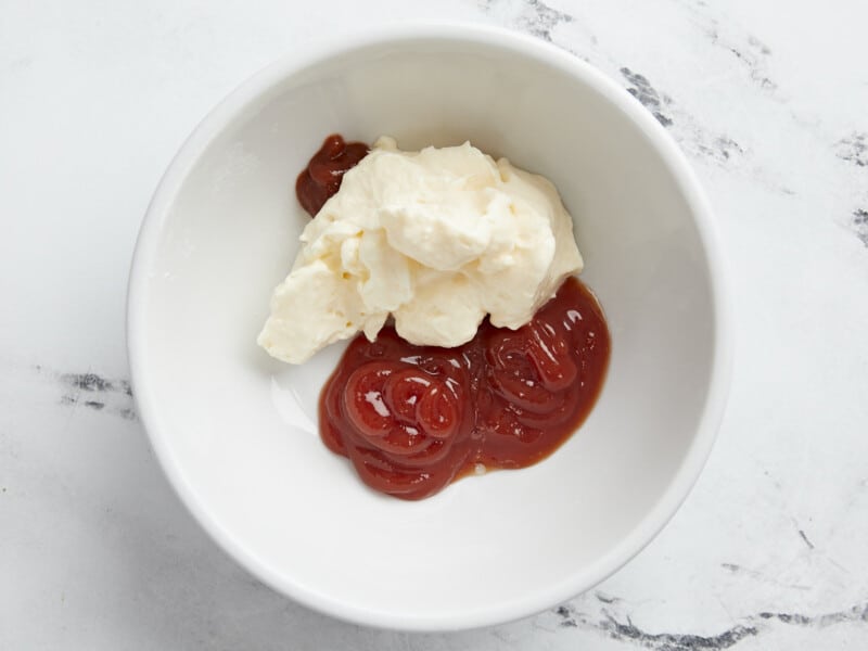 Overhead shot of Mayo Ketchup ingredients in a small white bowl surrounded by tostones.