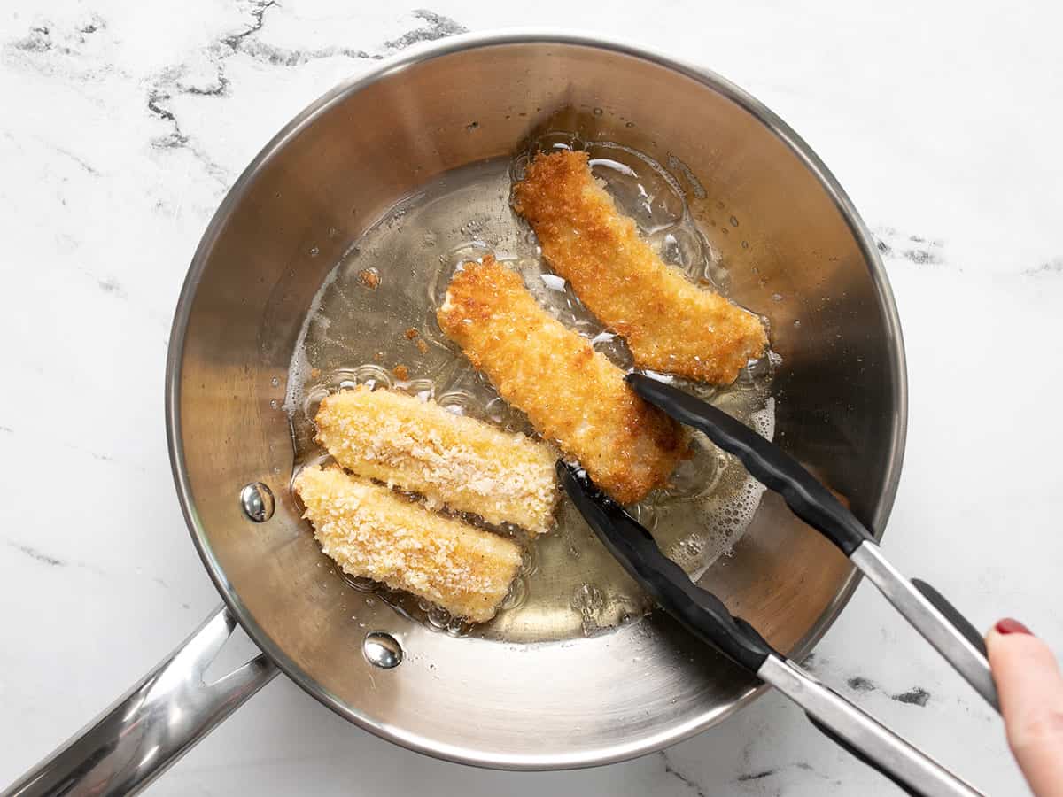 Fish sticks being fried in a small pan.