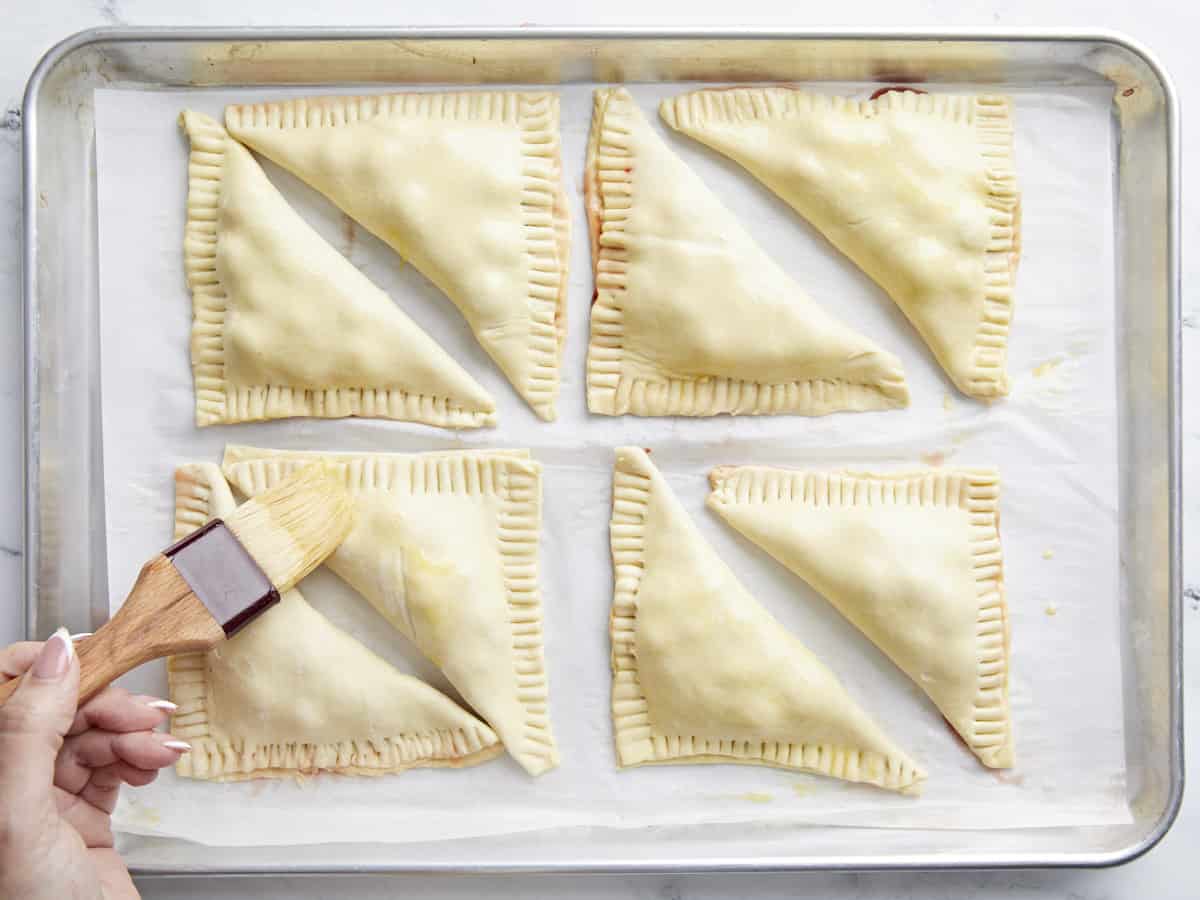 Egg being brushed on top of the puff pastry.