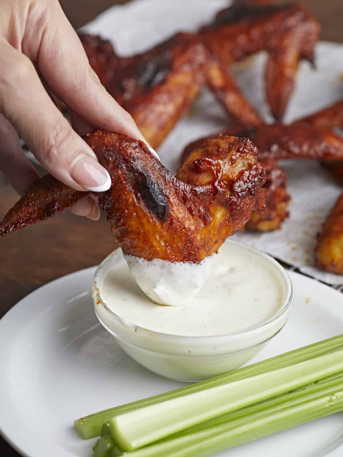 Side shot of BBQ Wing being dipped into bowl of ranch dressing.