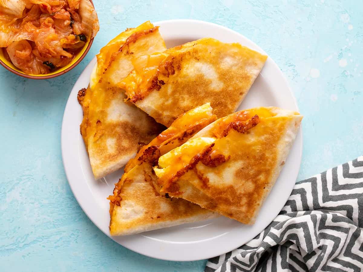 Overhead view of sliced kimchi quesadillas on a plate.