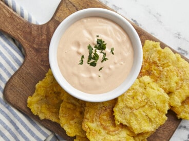 Overhead shot of Mayo ketchup in a small white bowl surrounded by tostones.