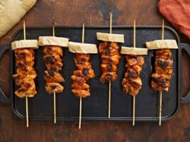 Overhead shot of Pinchos De Pollo on a black grill plate.