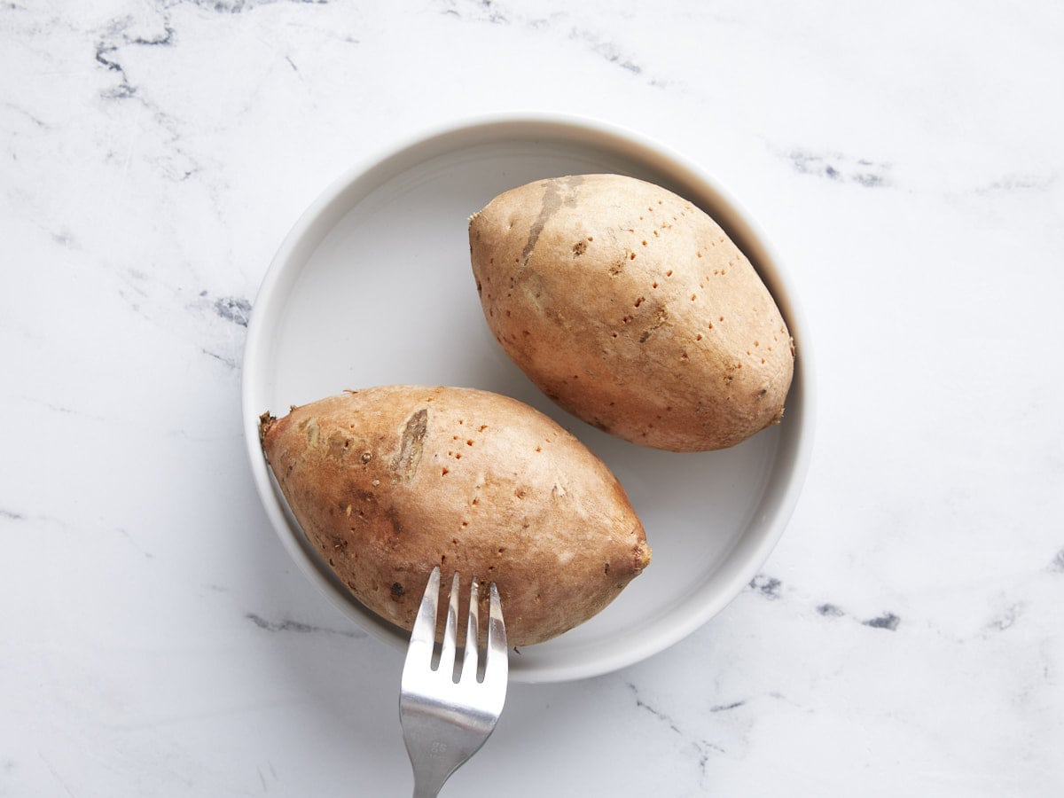 Sweet Potatoes being pierced with a fork.