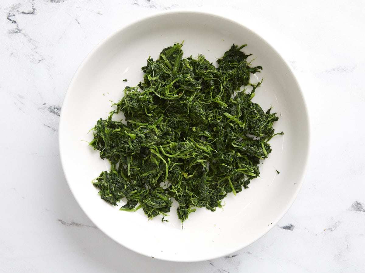 Thawed spinach squeezed dry in a bowl.