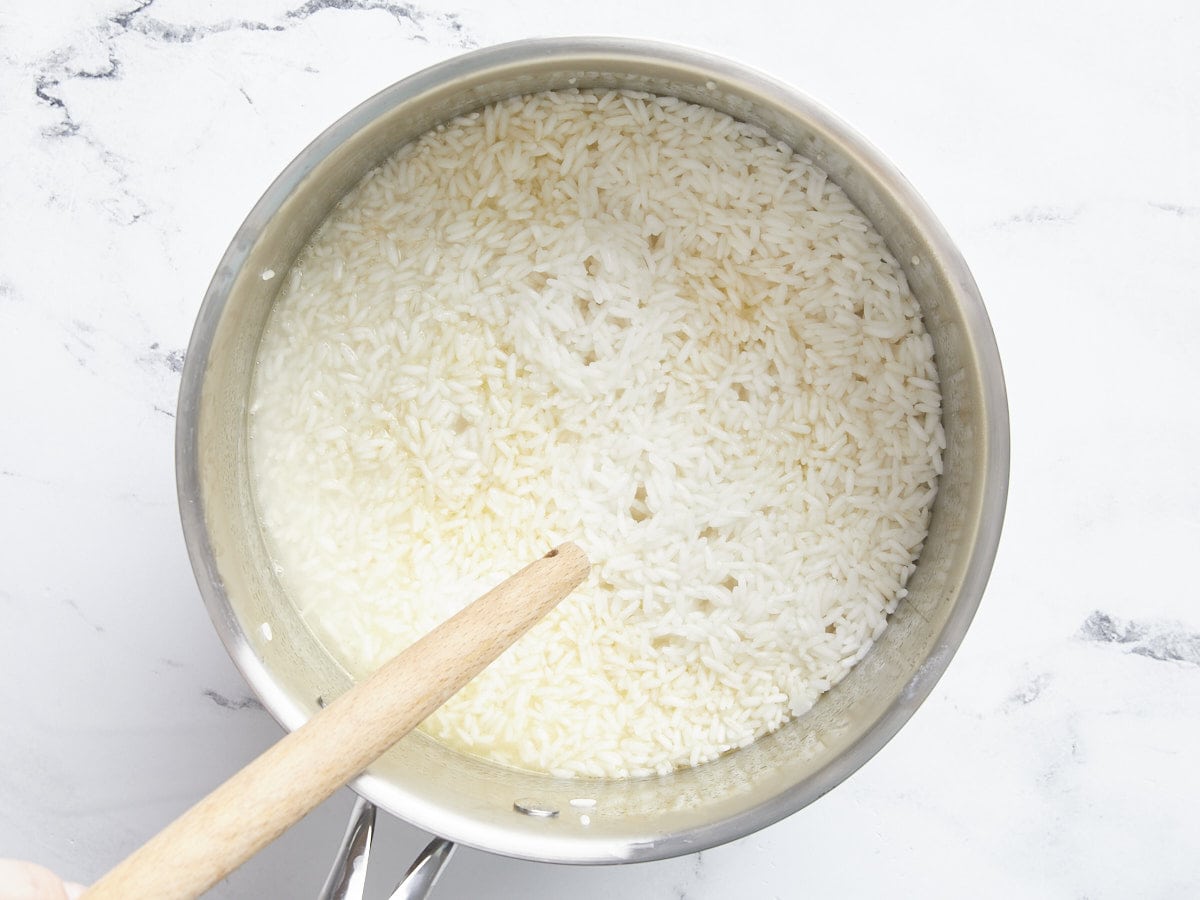 Half cooked rice in the pot, showing air vents in the surface.