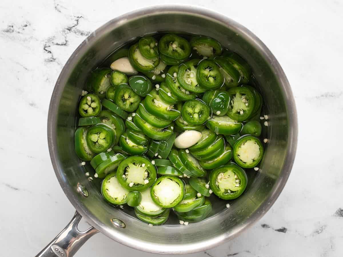 Sliced jalapeños and garlic added to the sauce pot with the brine.