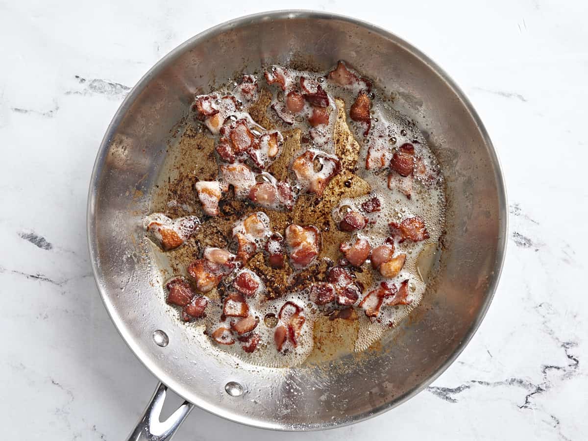 Bacon being cooked in a skillet until brown