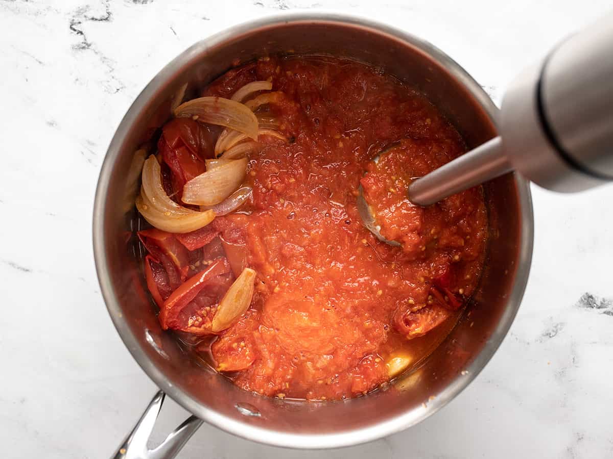 Vegetables being blended in the soup pot with an immersion blender.