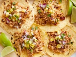 Close up overhead view of chipotle chicken tacos with limes on the side.