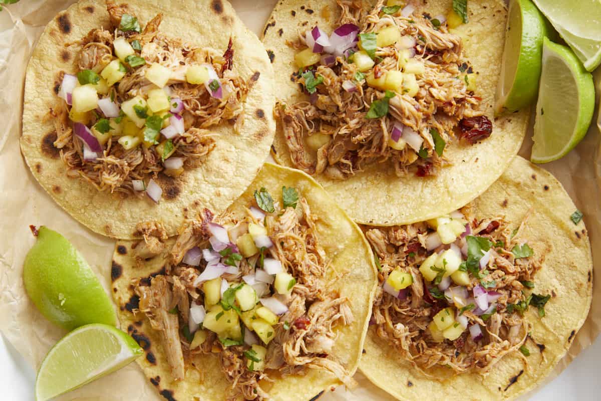 Close up overhead view of chipotle chicken tacos with limes on the side.