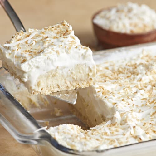 Side view of coconut cream pie bar being lifted out of the casserole dish.