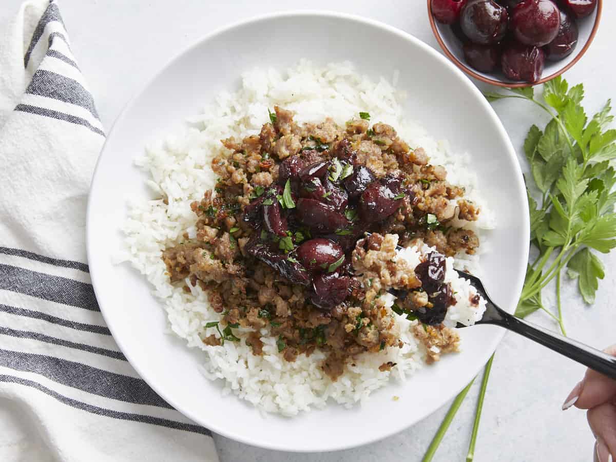 A fork digging into a pork and cherry rice bowl. 