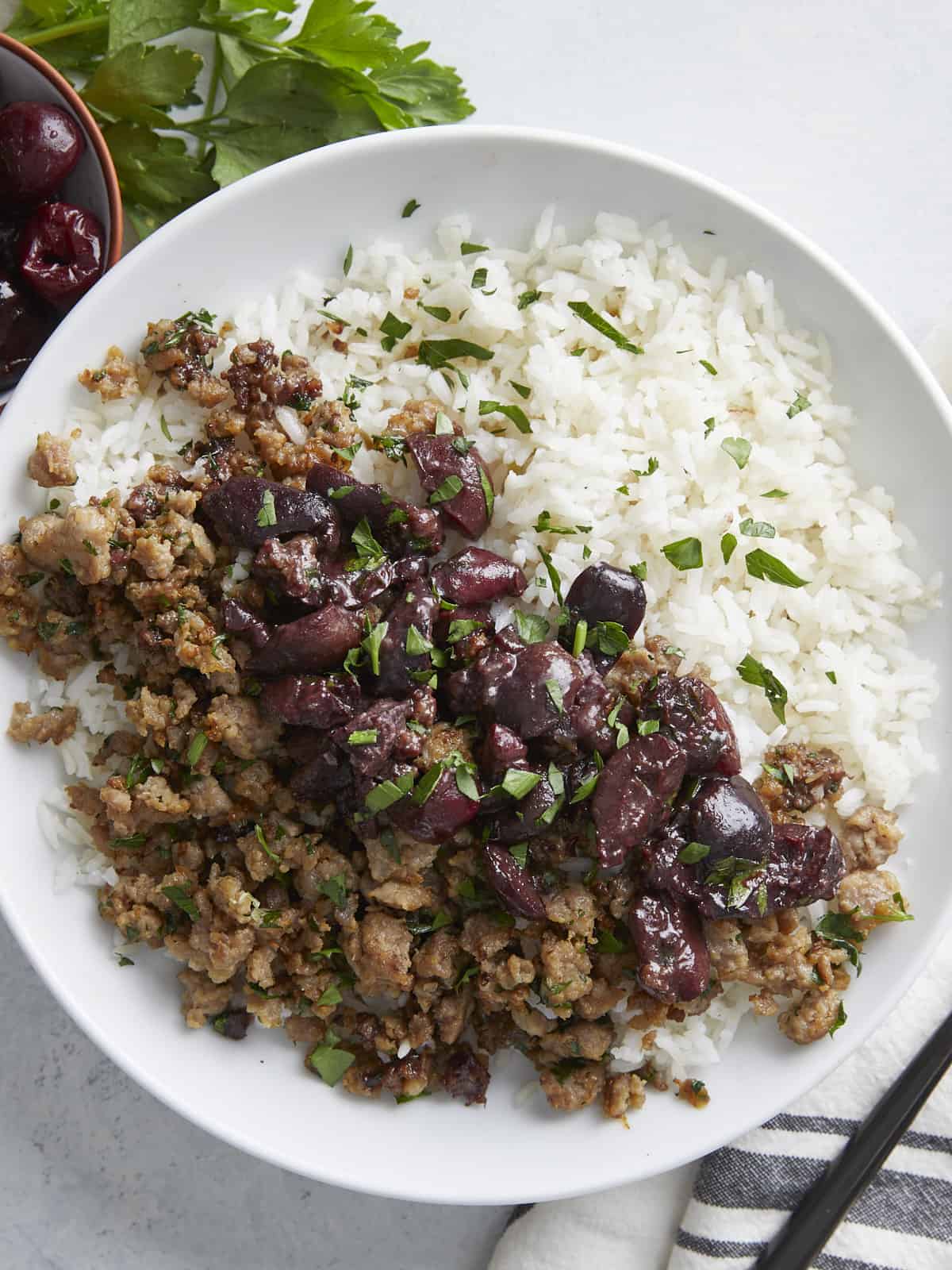 Overhead view of a pork and cherry rice bowl garnished with parsley.