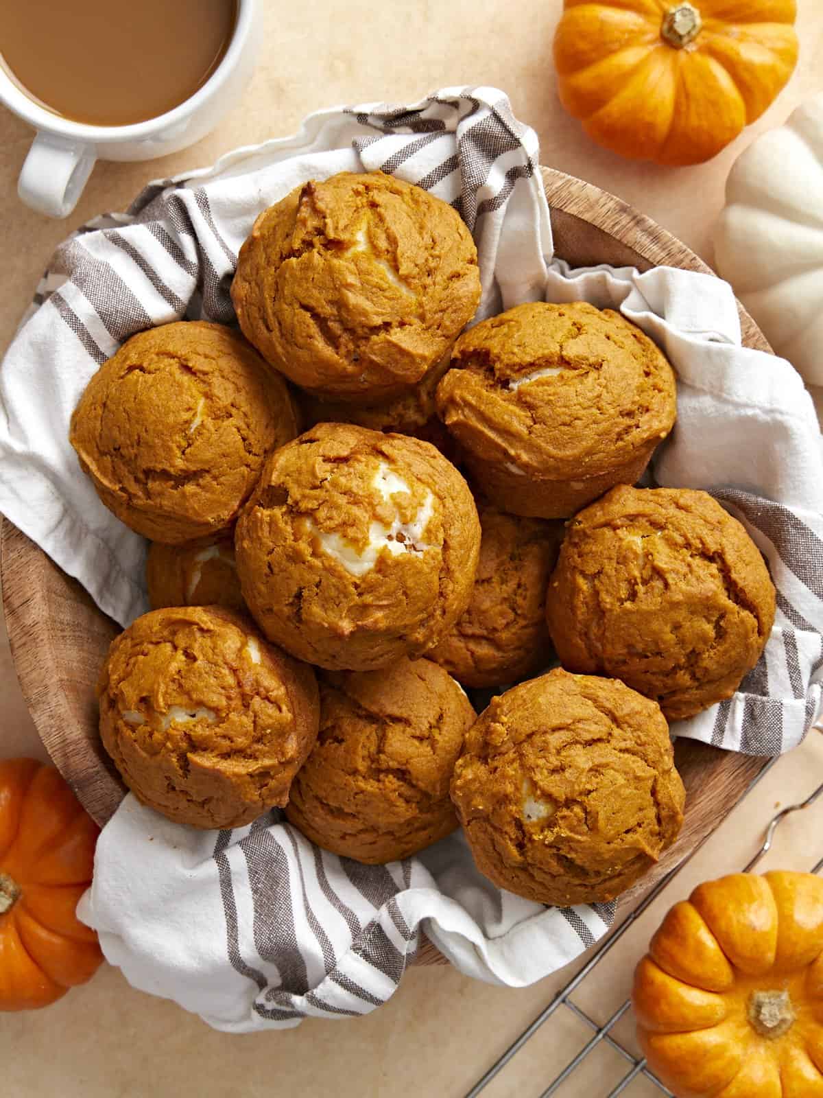 Overhead view of pumpkin muffins in a basket with a tea towel.