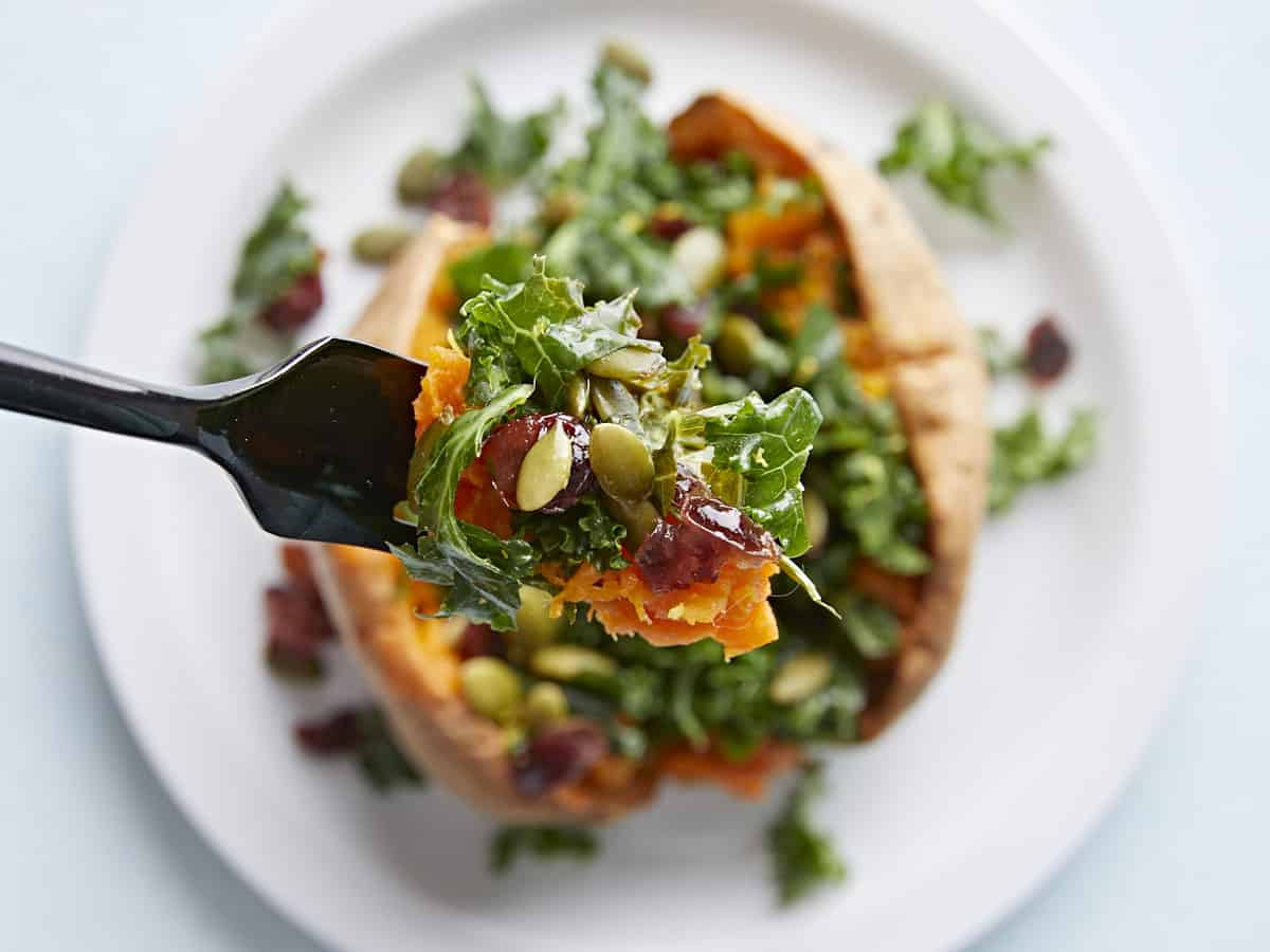 Close up of a forkful of stuffed sweet potato with the plate in the background.