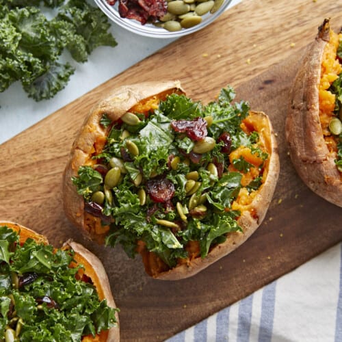 Three stuffed sweet potatoes on a wooden board.