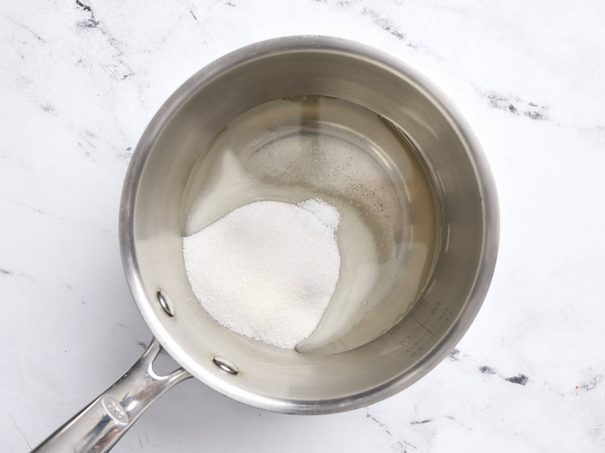 Overhead view of a small pot with corn syrup and sugar.