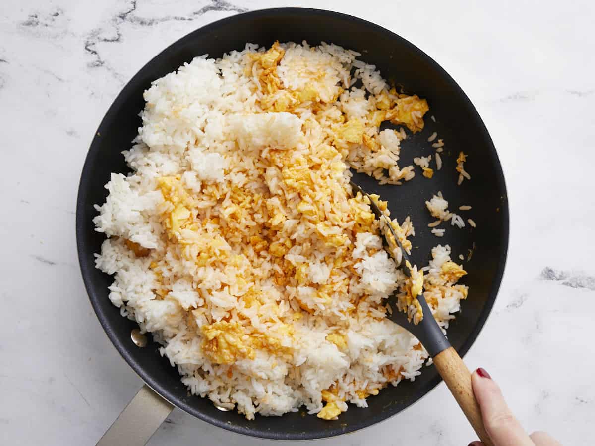 Rice being stirred into the eggs in the skillet.