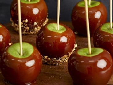 Caramel apples lined up in three rows, some with peanuts.