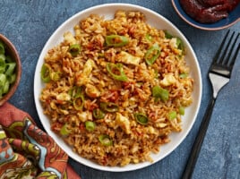 Overhead view of a plate full of scrambled eggs with rice, fork on the side.