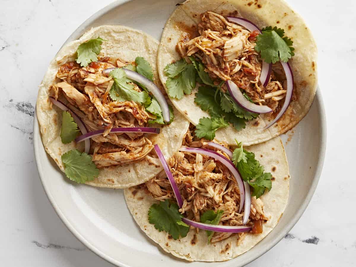 A plate full of three salsa chicken tacos.