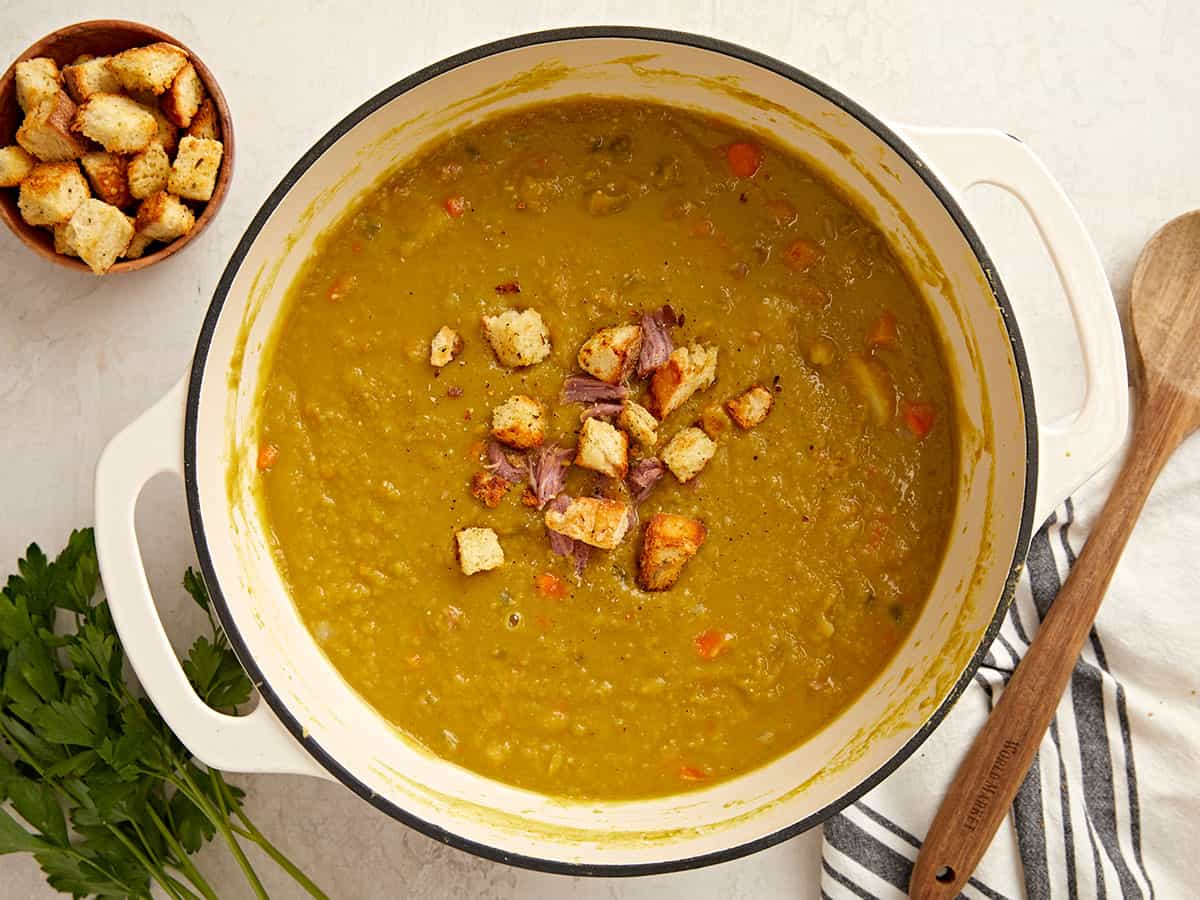 Overhead view of a dutch oven pot full of split pea soup with homemade croutons on top.