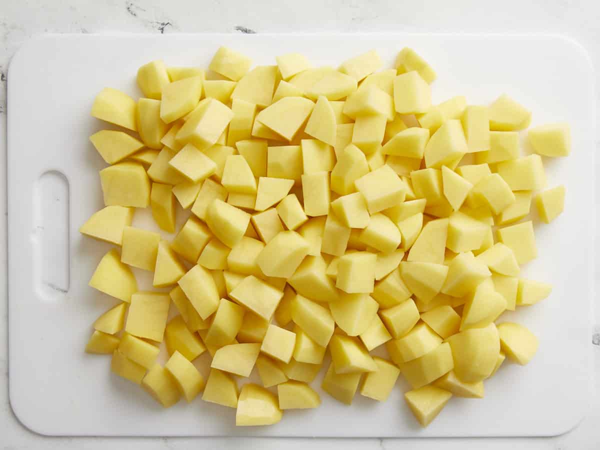 Yukon gold potatoes peeled and chopped on a cutting board.