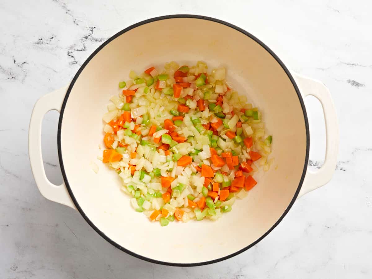 Overhead view of veggies being sauteed in a dutch oven pot.