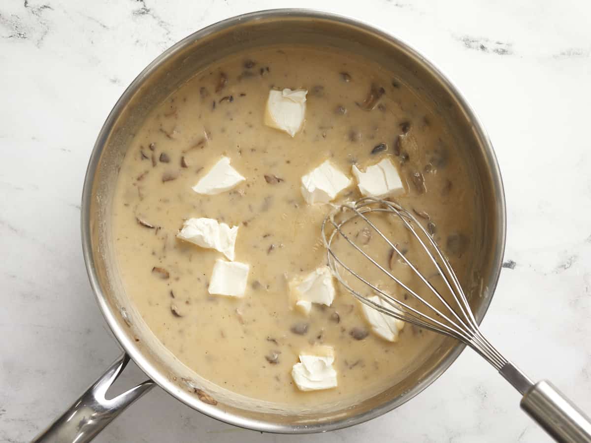 Cream cheese chunks added to the sauce in the skillet. 