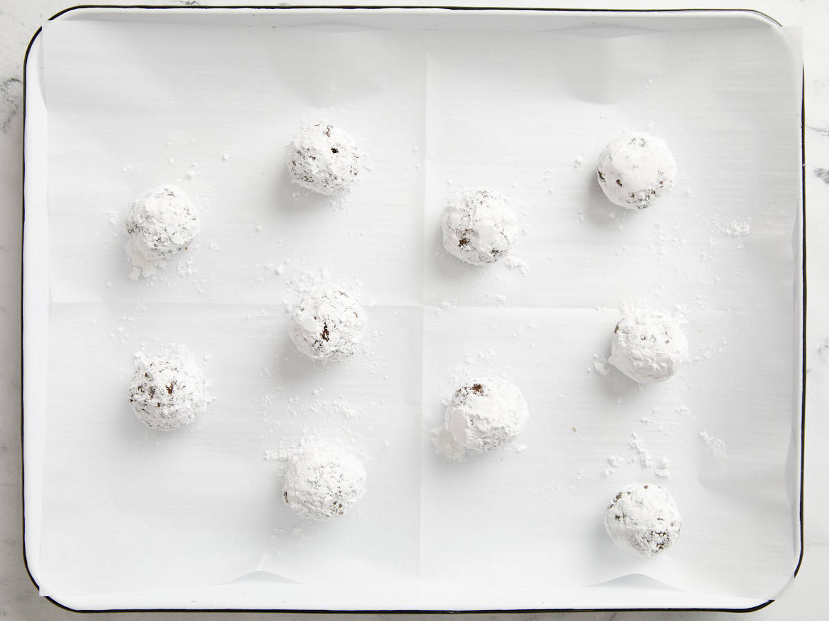 Chocolate crinkle cookies ready to bake on a parchment lined baking sheet. 