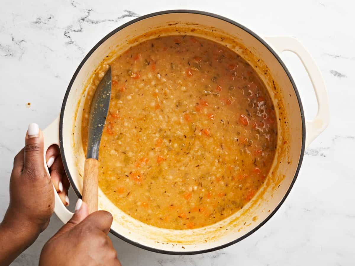 Overhead view of a few Navy Beans being smashed on the side of the pot. 