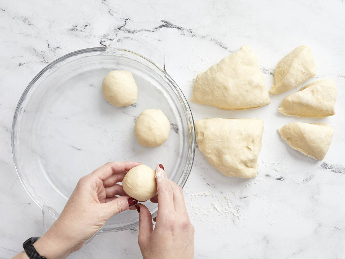 Bread dough being divided and shaped into rolls.