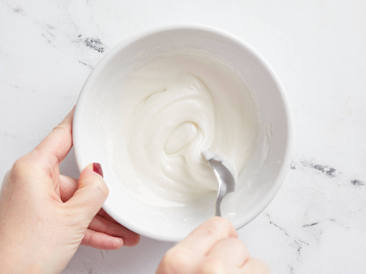 Powdered sugar icing in a bowl being stirred. 