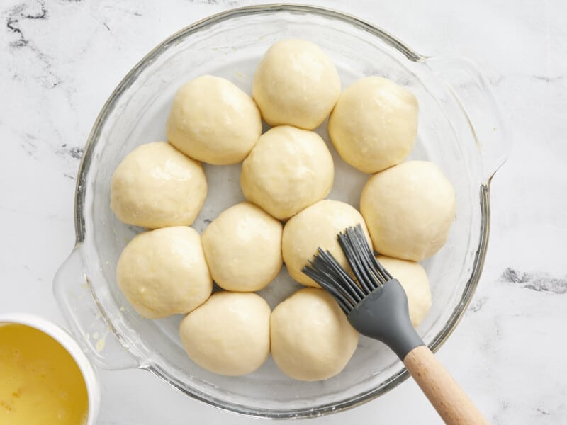 Rolls being brushed with an egg wash. 