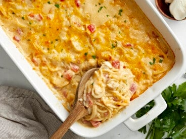 Overhead view of chicken spaghetti in a white casserole dish with a wooden spoon placed inside.