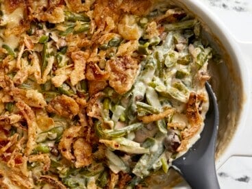 Super close up overhead shot of green bean casserole being scooped out of the baking dish.