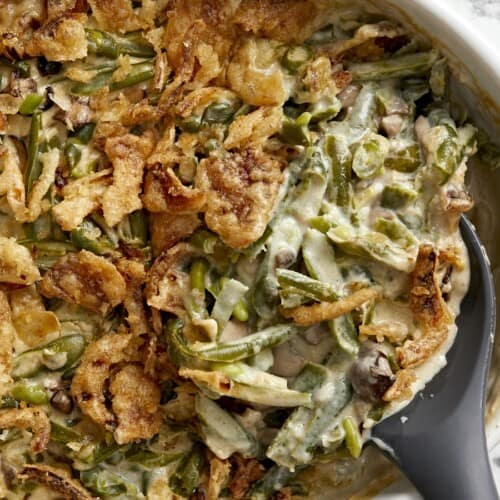 Super close up overhead shot of green bean casserole being scooped out of the baking dish.