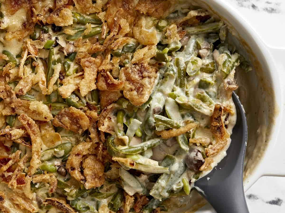 Super close up overhead shot of green bean casserole being scooped out of the baking dish. 