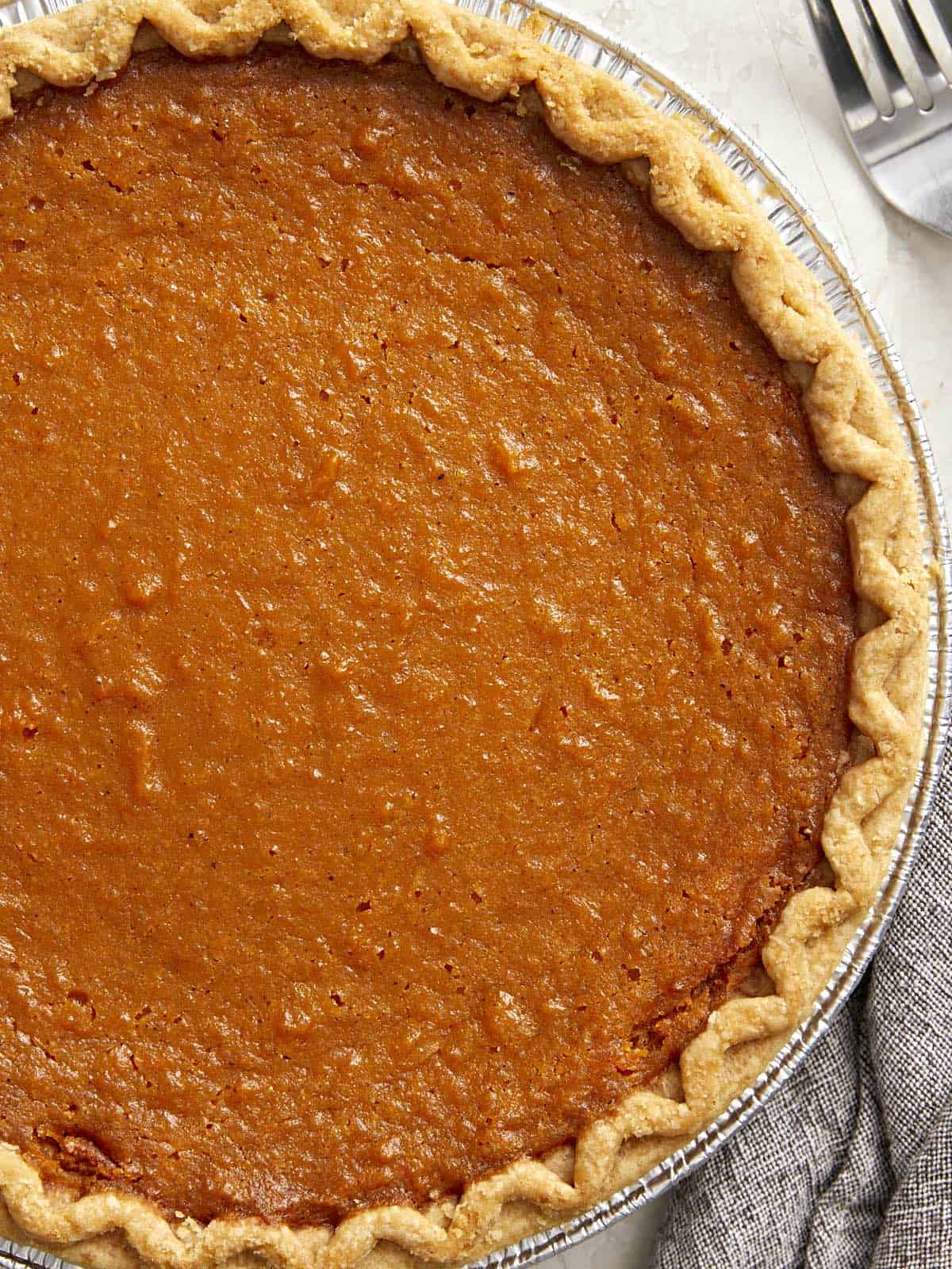 Overhead view of finished sweet potato pie with napkin and fork on the side.