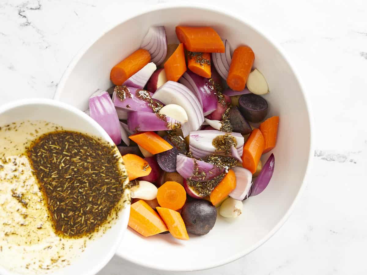 Seasoning being poured over the vegetables in a bowl. 