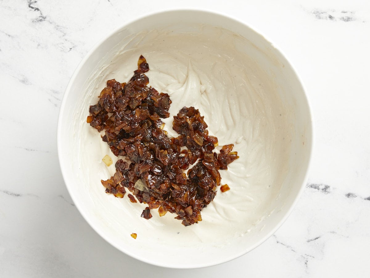 Caramelized onions added to the dip in the bowl. 