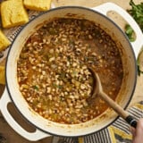 Overhead view of a pot of black-eyed peas with a wooden spoon.