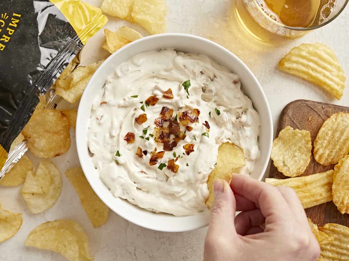 Overhead view of a chip being dipped into a bowl of French Onion Dip.