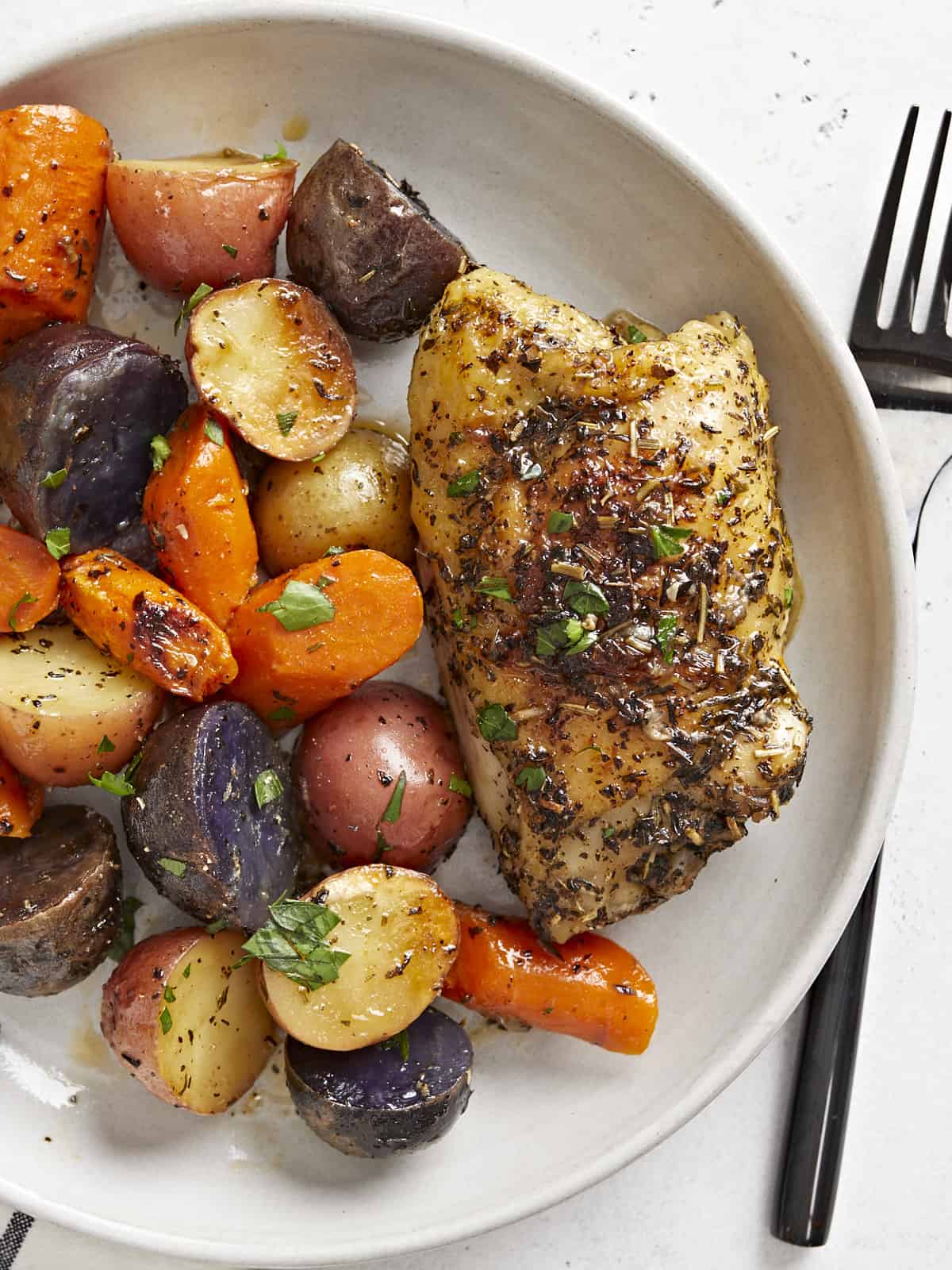 Overhead view of roasted chicken and vegetables on a plate. 