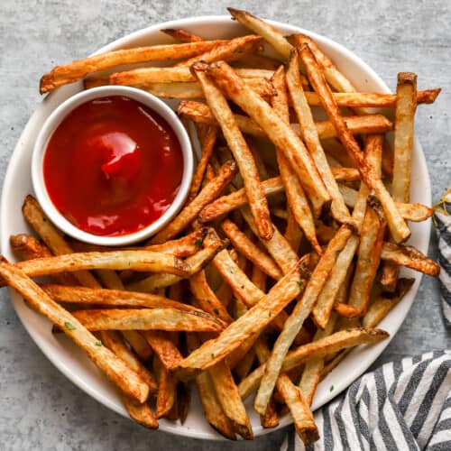 Overhead view of air fryer french fries on a white plate with ketchup.