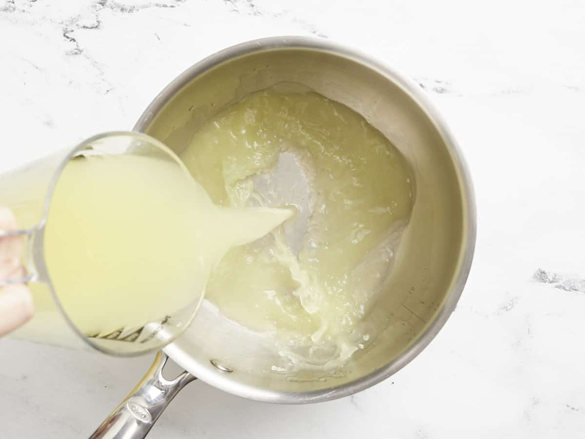 Chicken broth being poured into a saucepot.